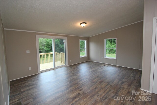unfurnished room with ornamental molding, dark wood-type flooring, a textured ceiling, vaulted ceiling, and baseboards