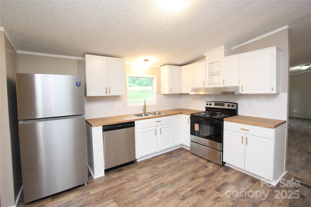 kitchen featuring appliances with stainless steel finishes, wooden counters, under cabinet range hood, a sink, and a textured ceiling