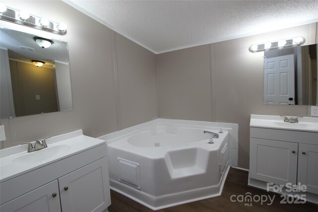 full bathroom with a textured ceiling, a bath, and two vanities