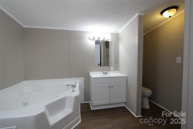 bathroom with wood finished floors, a bath, vanity, toilet, and a textured ceiling