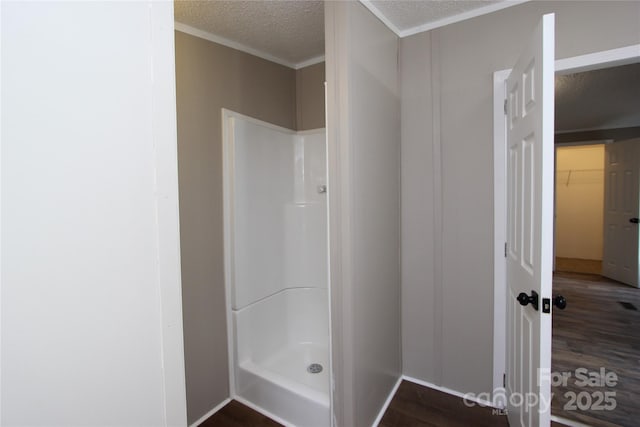 full bath featuring a shower stall, a textured ceiling, and wood finished floors