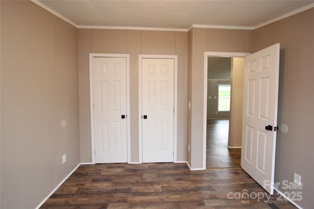 unfurnished bedroom featuring ornamental molding and dark wood-style floors