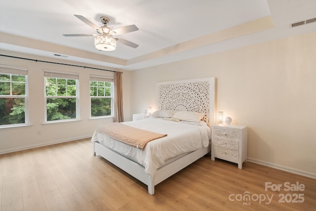 1104 Snowbird Ln, Waxhaw, NC 28173 - bedroom with a raised ceiling, baseboards, light wood-type flooring, and a ceiling fan
