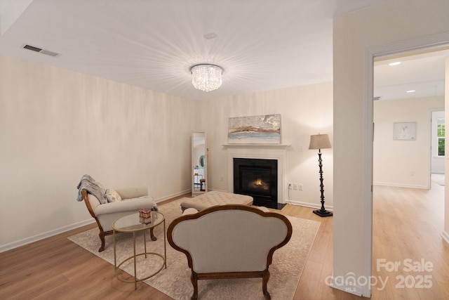 1104 Snowbird Ln, Waxhaw, NC 28173 - sitting room featuring wood finished floors, a fireplace with flush hearth, a chandelier, and baseboards