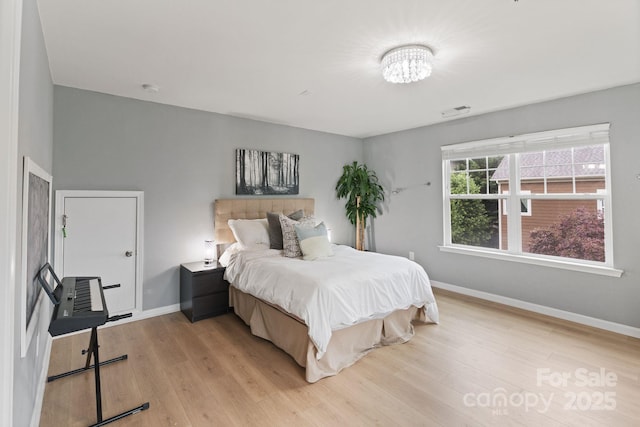 1104 Snowbird Ln, Waxhaw, NC 28173 - bedroom featuring baseboards, light wood-style flooring, and a chandelier