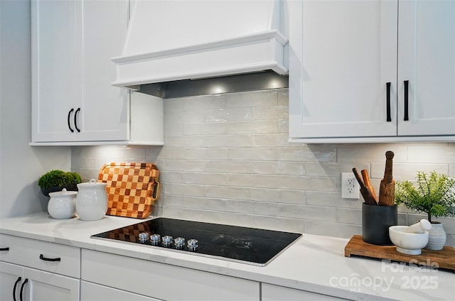 12055 Lavinia Ln, Charlotte, NC 28277 - kitchen with custom range hood, black electric stovetop, decorative backsplash, light countertops, and white cabinetry