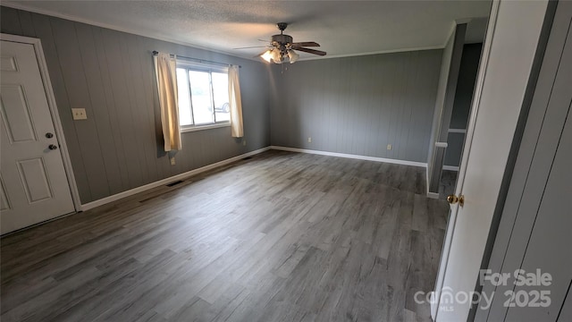 824 S Laurel St, Lincolnton, NC 28092 - empty room with ceiling fan, wood finished floors, crown molding, baseboards, and wooden walls