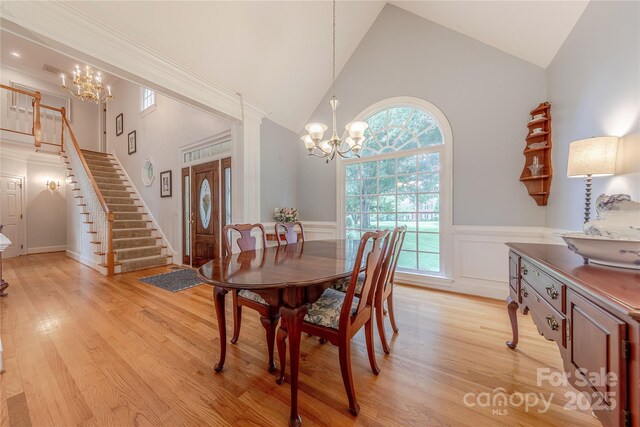 6024 Highview Rd, Weddington, NC 28104 - dining space featuring a chandelier, stairs, high vaulted ceiling, wainscoting, and light wood-style floors