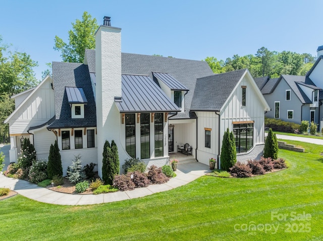 14228 Ryker Way, Davidson, NC 28036 - rear view of house with board and batten siding, a standing seam roof, a chimney, and a lawn