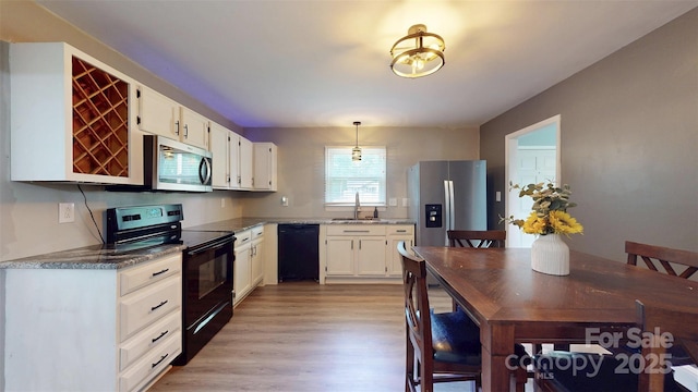 8905 Vagabond Rd, Mint Hill, NC 28227 - kitchen with black appliances, a sink, white cabinets, light wood-style floors, and decorative light fixtures