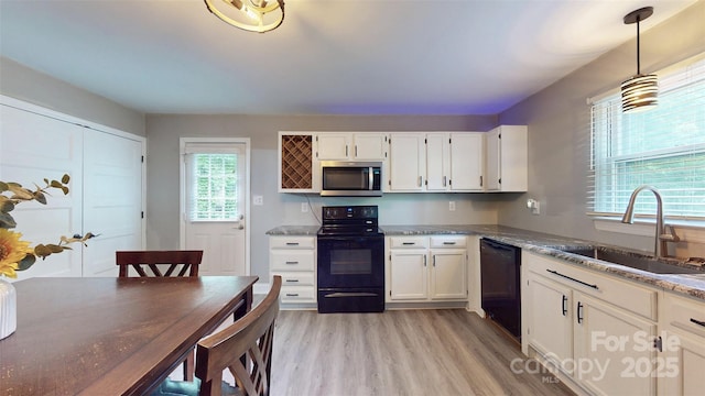 8905 Vagabond Rd, Mint Hill, NC 28227 - kitchen with black appliances, a sink, light wood finished floors, white cabinets, and hanging light fixtures