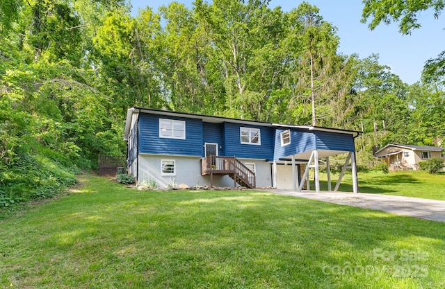 raised ranch featuring concrete driveway, stairs, a front yard, an attached garage, and a carport