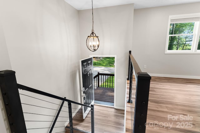 staircase with wood finished floors, baseboards, and a chandelier