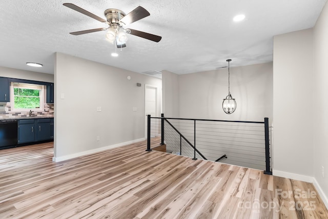 spare room with a sink, light wood-type flooring, baseboards, a ceiling fan, and a chandelier
