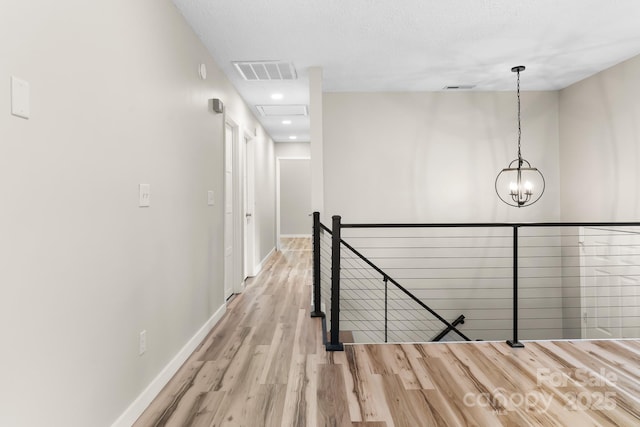 hall with an upstairs landing, wood finished floors, baseboards, recessed lighting, and a chandelier
