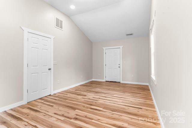 spare room featuring lofted ceiling, light wood finished floors, and baseboards