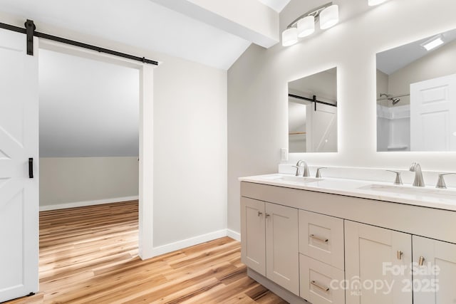 bathroom featuring vaulted ceiling, wood finished floors, double vanity, and baseboards