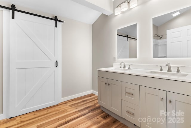 full bathroom featuring lofted ceiling, wood finished floors, baseboards, double vanity, and a shower