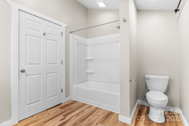 full bath featuring wood finished floors, toilet, baseboards, and washtub / shower combination