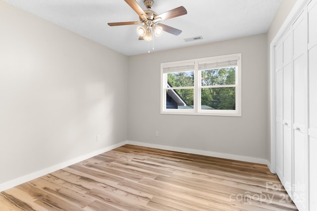 unfurnished bedroom featuring a closet, light wood-type flooring, baseboards, and ceiling fan