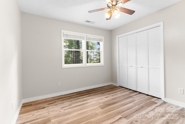 unfurnished bedroom featuring light wood-type flooring, baseboards, a closet, and a ceiling fan