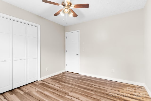 unfurnished bedroom with light wood-style flooring, baseboards, a closet, and ceiling fan