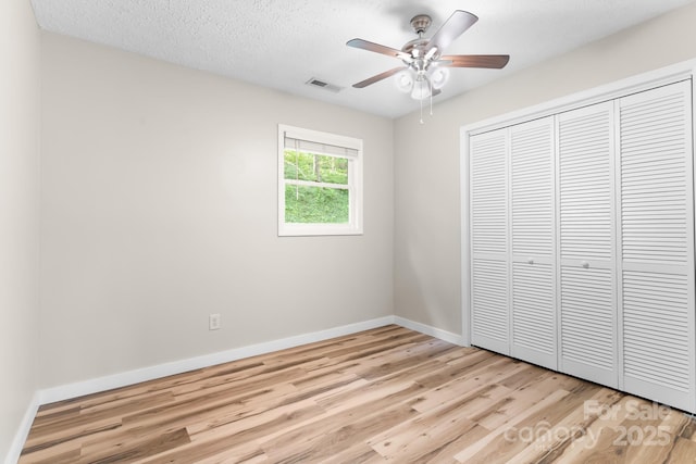 unfurnished bedroom with light wood-type flooring, baseboards, a closet, and a ceiling fan