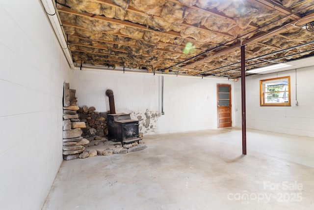 basement with a wood stove and concrete block wall