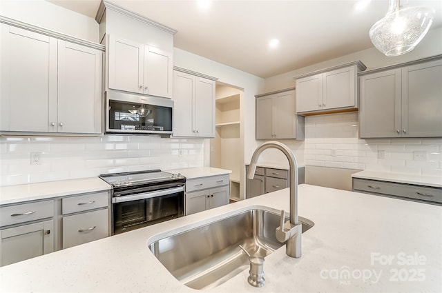 kitchen with stainless steel appliances, gray cabinets, a sink, tasteful backsplash, and recessed lighting