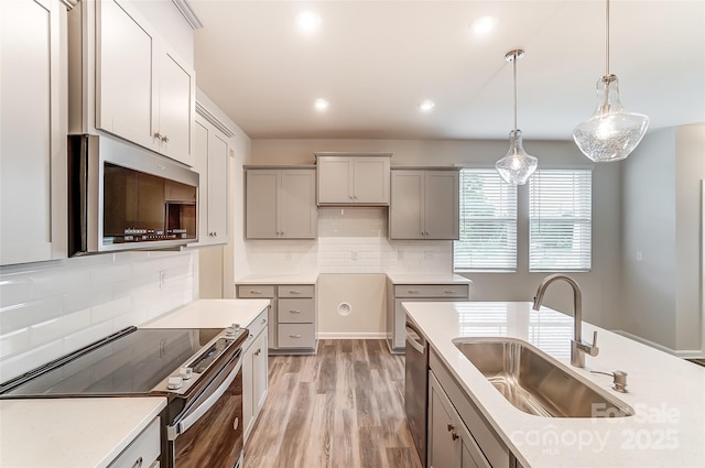 kitchen with stainless steel appliances, a sink, gray cabinetry, tasteful backsplash, and recessed lighting