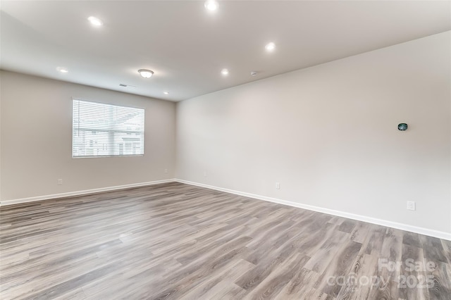 empty room featuring wood finished floors, baseboards, and recessed lighting