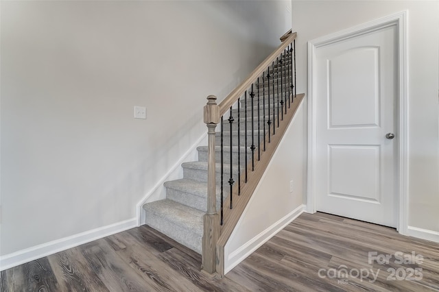 staircase featuring wood finished floors and baseboards