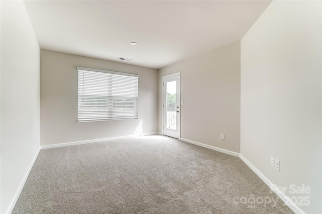 spare room featuring carpet floors and baseboards