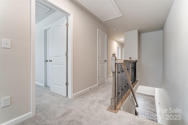hall with an upstairs landing, attic access, and baseboards