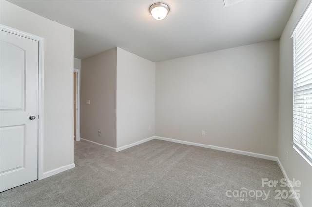 spare room featuring light carpet, baseboards, and healthy amount of natural light
