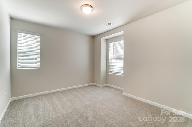 spare room featuring light carpet and baseboards