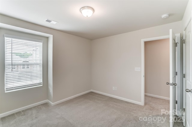 spare room with light colored carpet, a smoke detector, and baseboards
