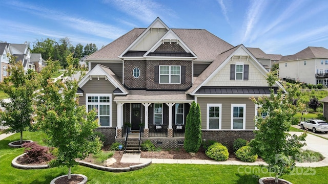 220 Forsythia Ln, Tega Cay, SC 29708 - craftsman-style house featuring a standing seam roof, a porch, a front yard, a shingled roof, and brick siding