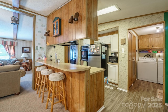 2310 Alexis Lucia Rd, Stanley, NC 28164 - kitchen with washing machine and dryer, wallpapered walls, light wood-style flooring, freestanding refrigerator, and black microwave