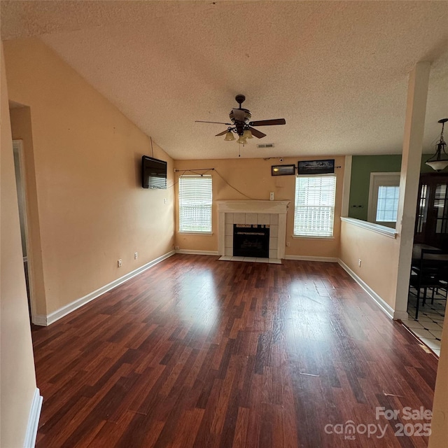 3012 Longspur Dr, Matthews, NC 28105 - unfurnished living room featuring a textured ceiling, dark wood finished floors, a ceiling fan, a tiled fireplace, and baseboards