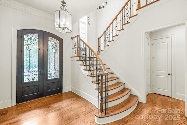 18843 Flat Shoals Dr, Cornelius, NC 28031 - foyer entrance featuring french doors, arched walkways, wood finished floors, stairs, and ornamental molding
