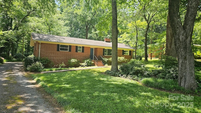 7021 Linda Lake Dr, Charlotte, NC 28215 - ranch-style house featuring driveway, a chimney, brick siding, a front lawn, and a forest view