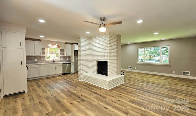 7021 Linda Lake Dr, Charlotte, NC 28215 - unfurnished living room with a sink, a ceiling fan, recessed lighting, light wood-style flooring, and a brick fireplace
