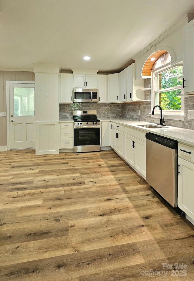 7021 Linda Lake Dr, Charlotte, NC 28215 - kitchen featuring appliances with stainless steel finishes, a sink, light wood-style flooring, backsplash, and recessed lighting