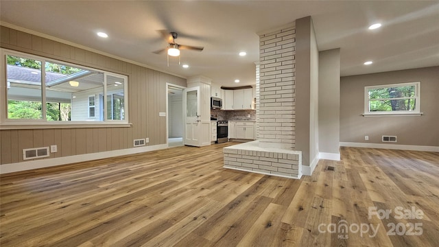 7021 Linda Lake Dr, Charlotte, NC 28215 - unfurnished living room with ornamental molding, baseboards, light wood-style floors, ceiling fan, and recessed lighting