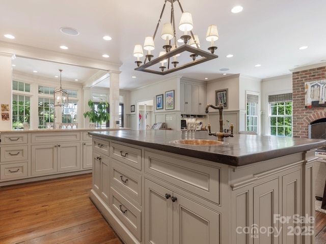 2410 Vernon Dr, Charlotte, NC 28211 - kitchen featuring a chandelier, light wood-style flooring, crown molding, dark countertops, and hanging light fixtures