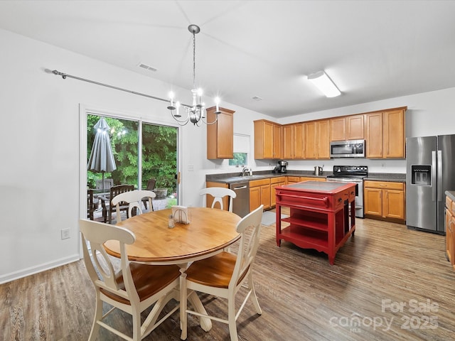 2306 Nettleton Ct, Matthews, NC 28105 - kitchen with appliances with stainless steel finishes, dark countertops, open shelves, wood finished floors, and a chandelier
