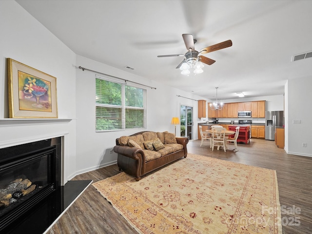 2306 Nettleton Ct, Matthews, NC 28105 - living area featuring ceiling fan, dark wood-style flooring, a chandelier, a glass covered fireplace, and baseboards