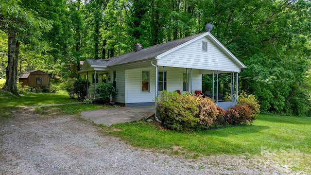 715 Broadway St NW, Lenoir, NC 28645 - view of front of house with a front lawn, a chimney, covered porch, and a storage shed