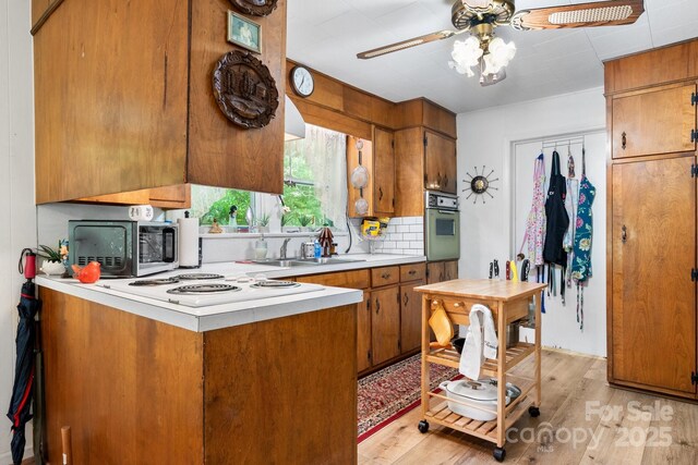 715 Broadway St NW, Lenoir, NC 28645 - kitchen with a sink, wall oven, brown cabinetry, light countertops, and light wood-type flooring